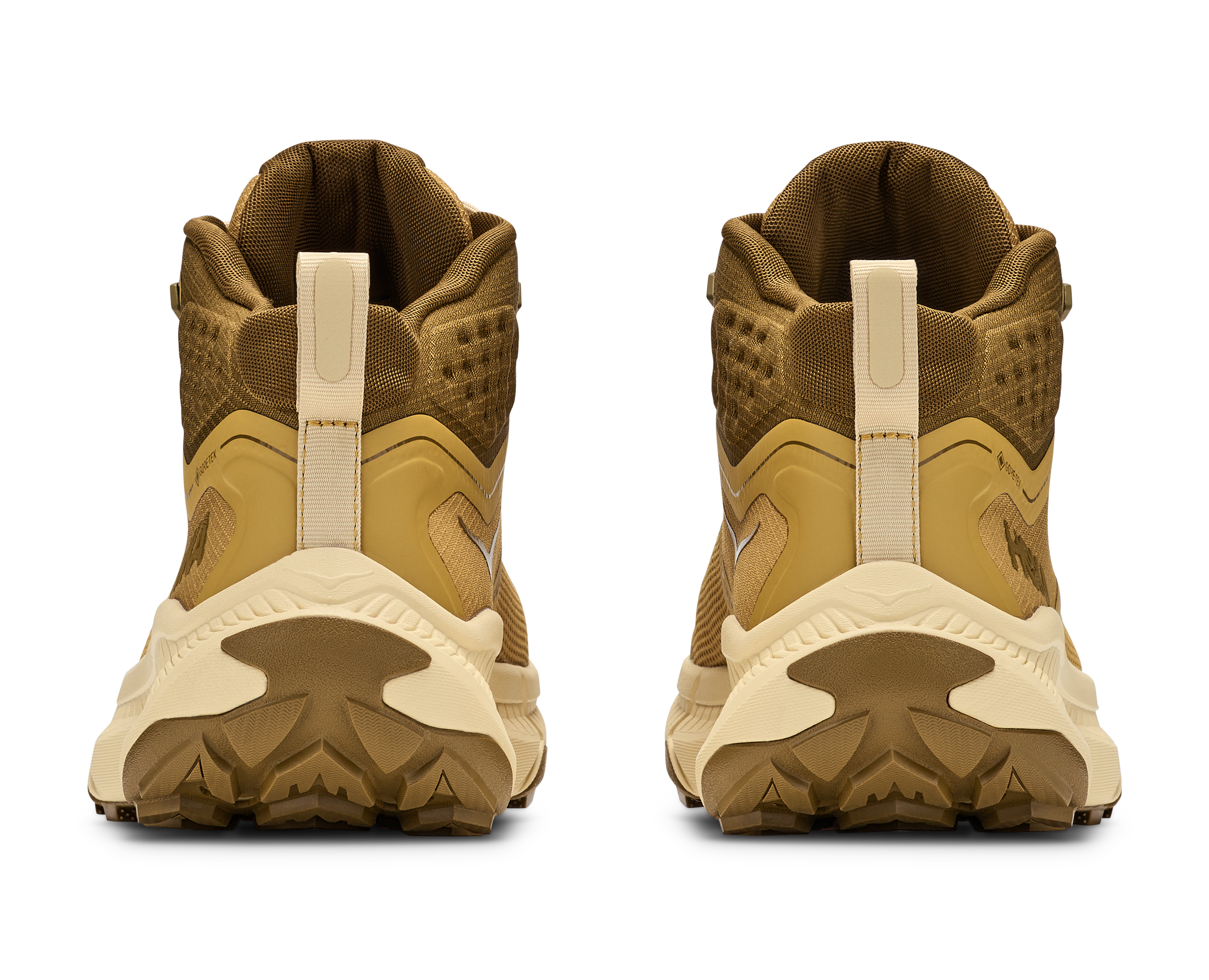 A pair of tan and brown mid-height athletic boots shown from the back, featuring textured mesh uppers, pull tabs, and chunky off-white and brown soles, set against a plain white background.