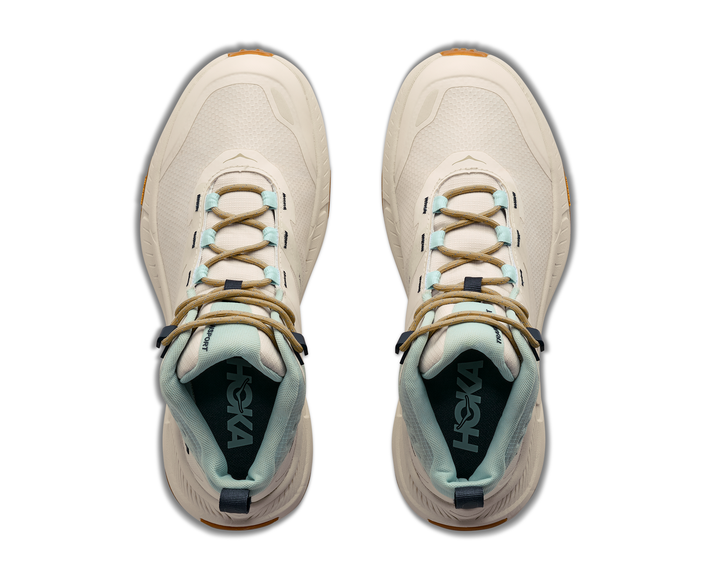 A pair of HOKA hiking shoes shown from a top-down view on a solid white background. The shoes are primarily cream-colored with light blue accents on the laces and lining, tan laces, and a small orange accent on the toe bumper.