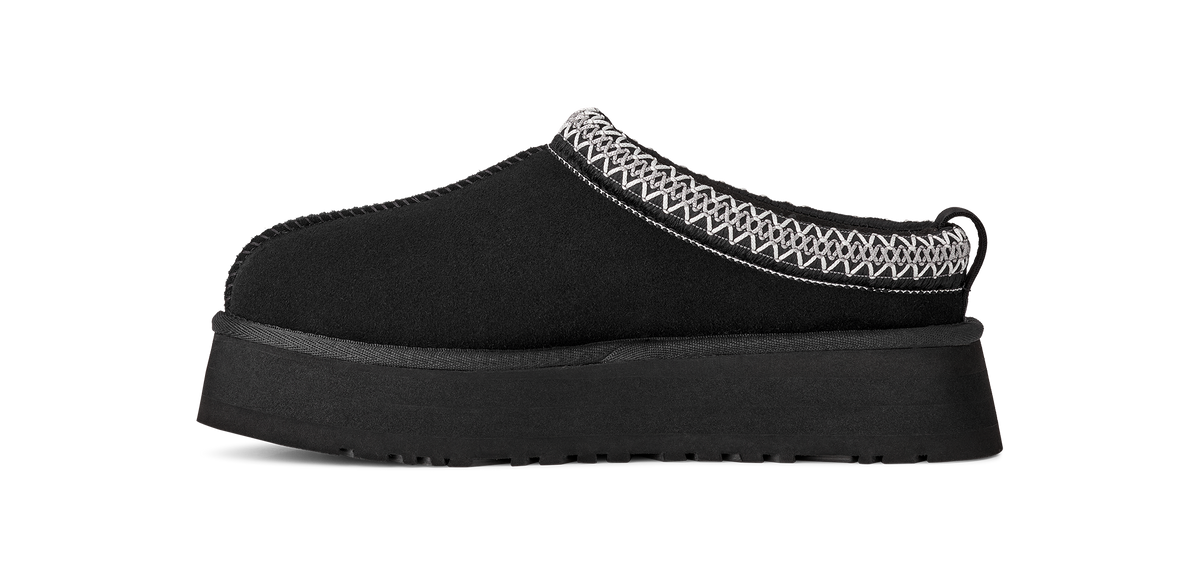 A single black slip-on clog-style shoe with a thick platform sole and a white geometric patterned trim along the top edge, shown against a plain white background.