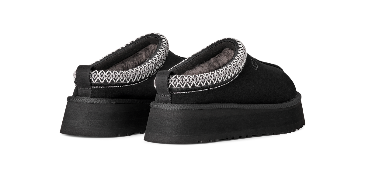 A pair of black slip-on platform slippers with a textured knit trim around the collar, shown against a plain white background.