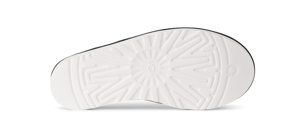 The white textured outsole of a shoe, showing a circular sunburst pattern and a small circular logo near the rear, photographed on a clean white background.