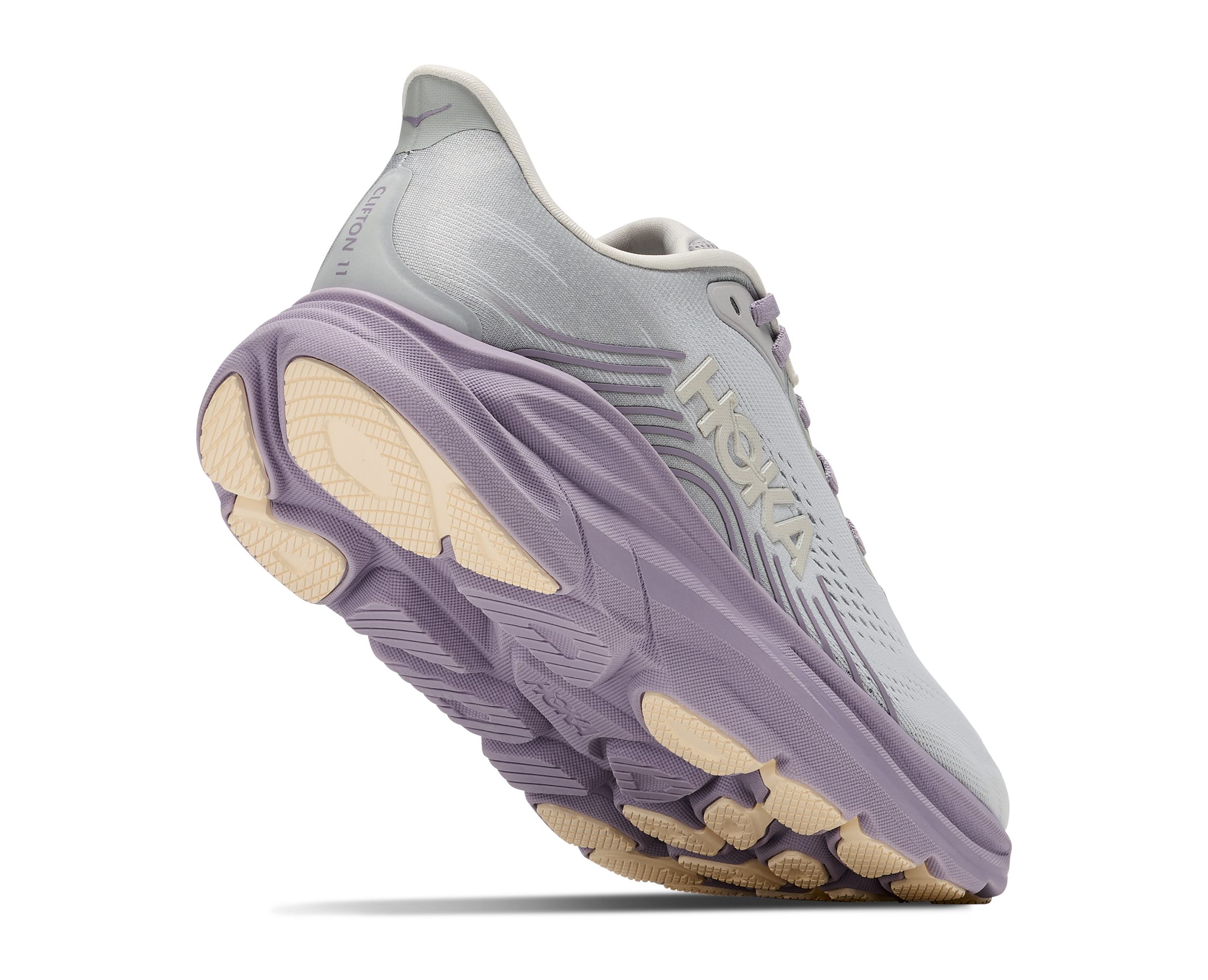 A Hoka running shoe in light gray and lavender purple with beige accents on the midsole and outsole, shown from a three-quarters angle on a white background.