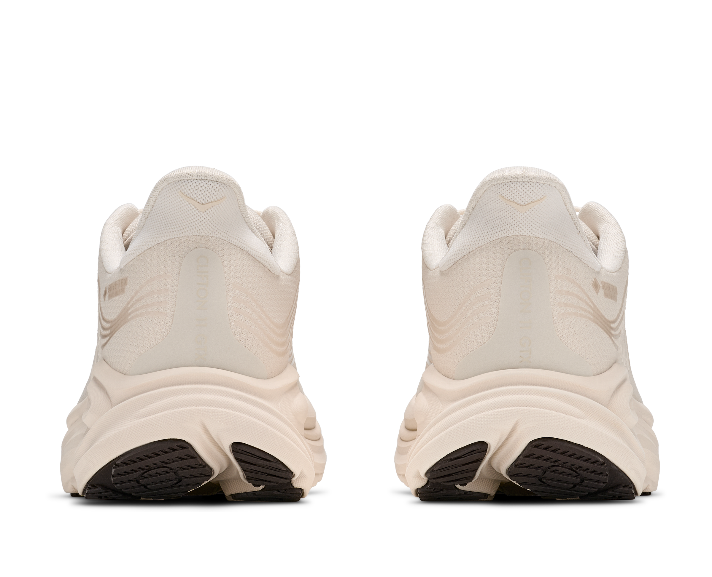 Pair of beige running shoes with black soles on a white background