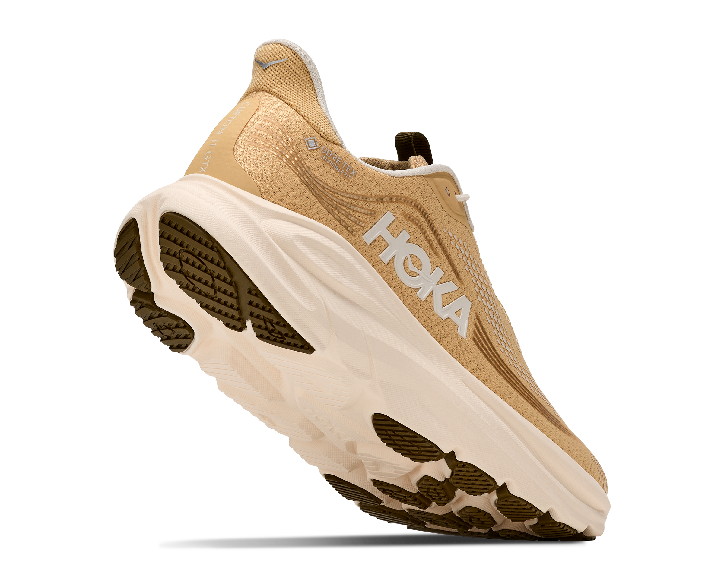 A Hoka running shoe in tan and off-white with dark brown lugged outsole details, shown from a three-quarters angle on a white background.