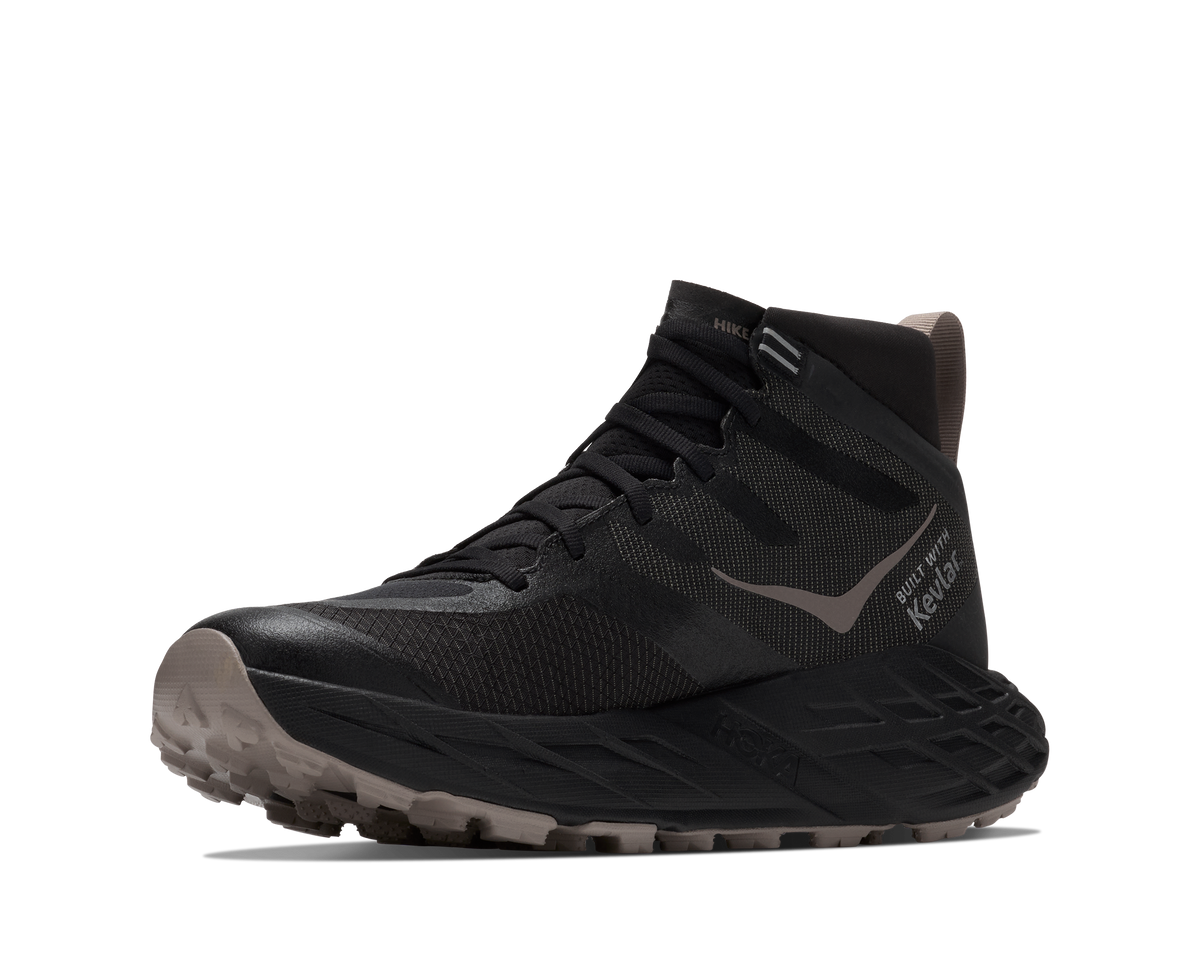 A black mid-cut trail running shoe with a textured mesh upper, black laces, a gray side logo, and a rugged gray and black outsole, shown against a plain white background.