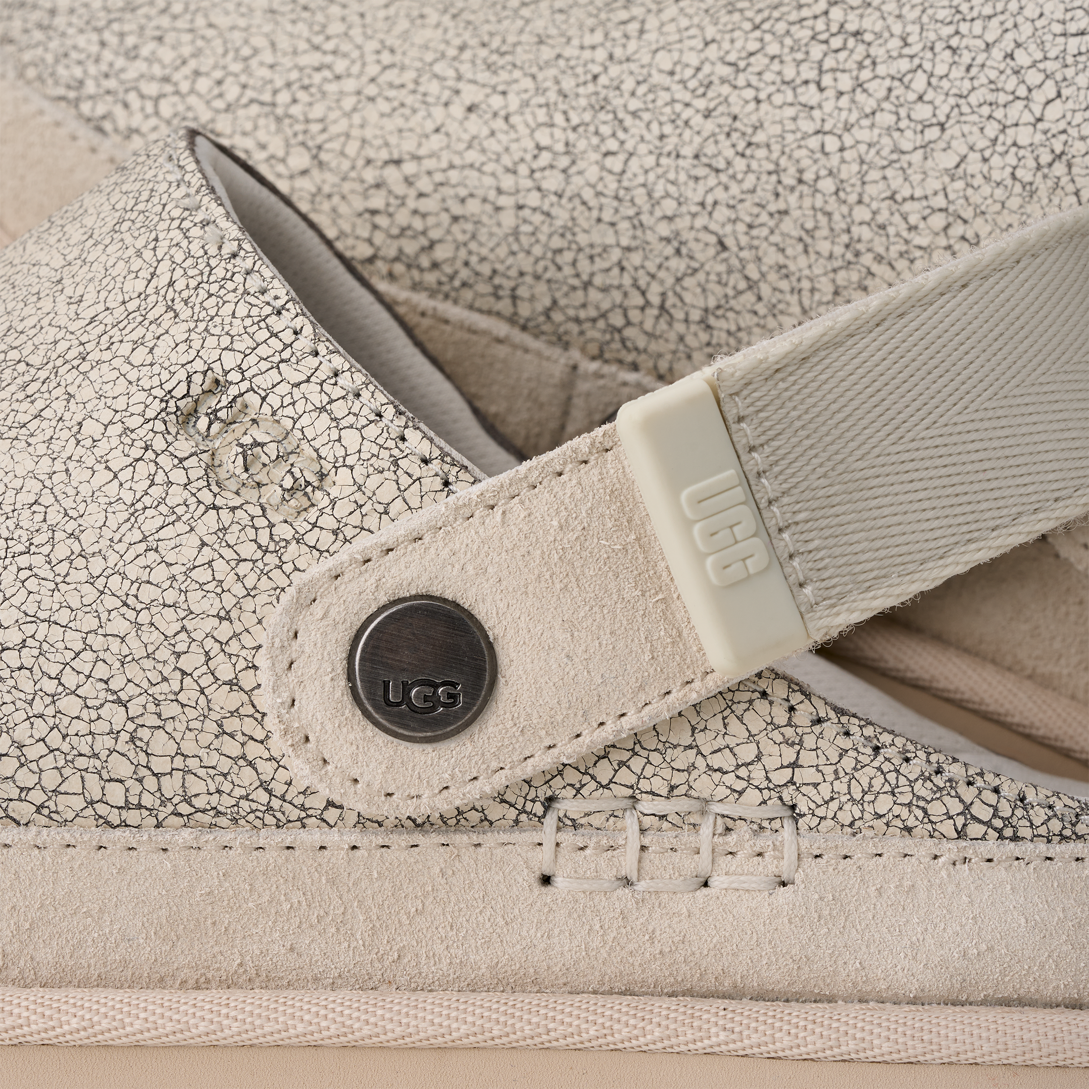 Close-up of a beige UGG shoe with textured surface and visible brand logo.