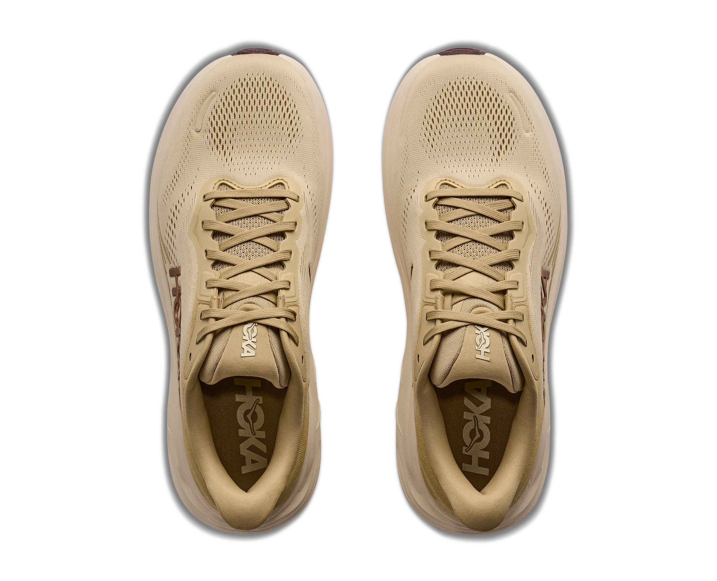 Pair of beige running shoes with 'Hoka' branding on a white background