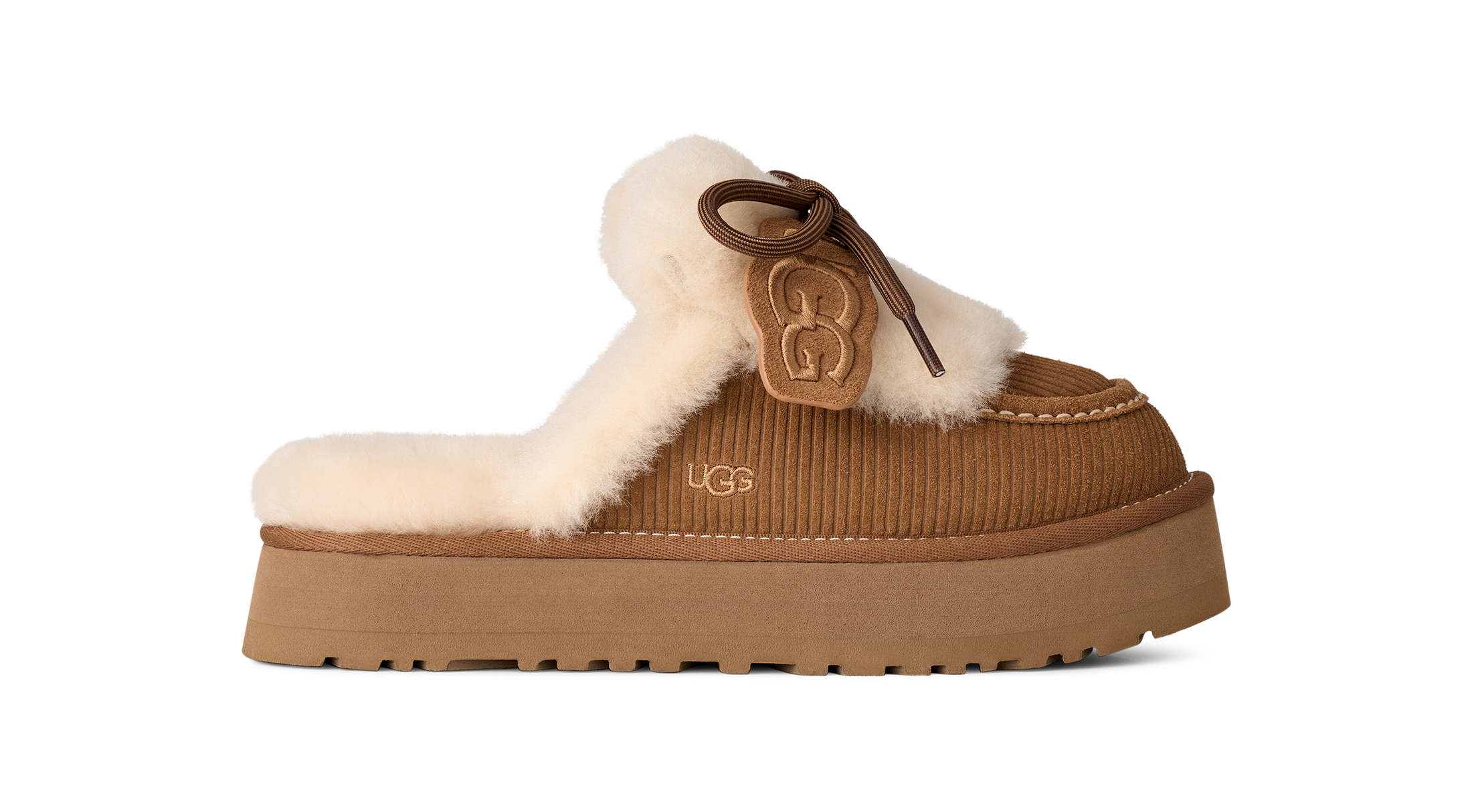 A UGG platform mule slipper in brown corduroy with a cream shearling lining and a brown leather bow detail featuring an embossed UGG logo, shown against a plain white background.