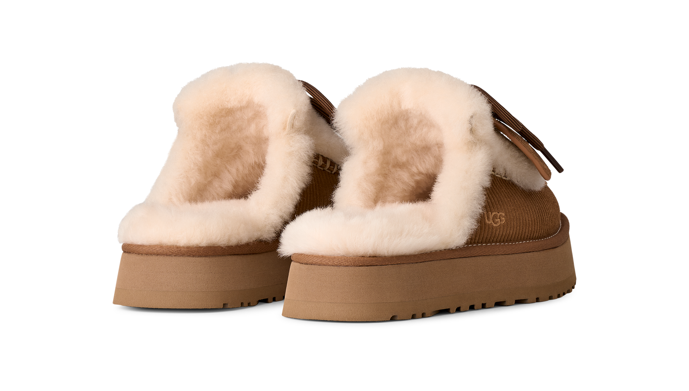 A pair of UGG platform slippers with thick tan soles and fluffy cream shearling lining, shown from a three-quarters angle on a white background.