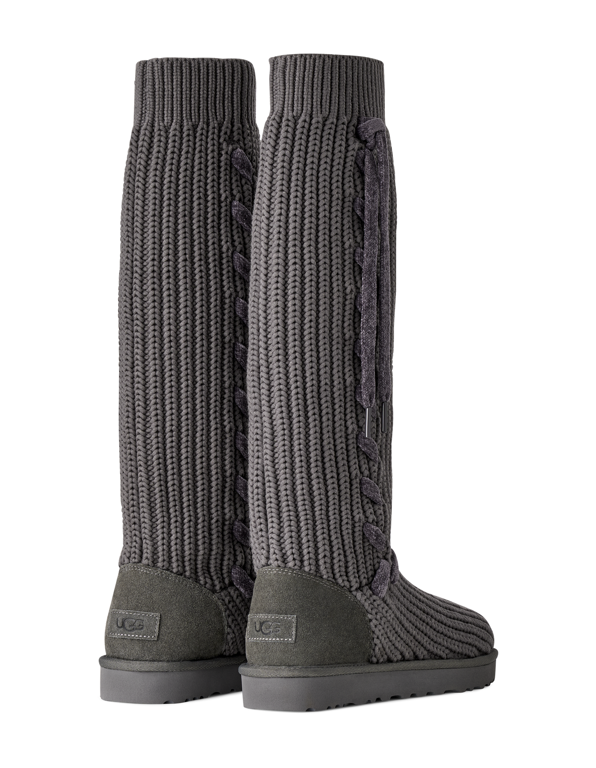A pair of dark gray UGG knee-high knit boots with textured cable and rib patterns, shown from the back on a white background.