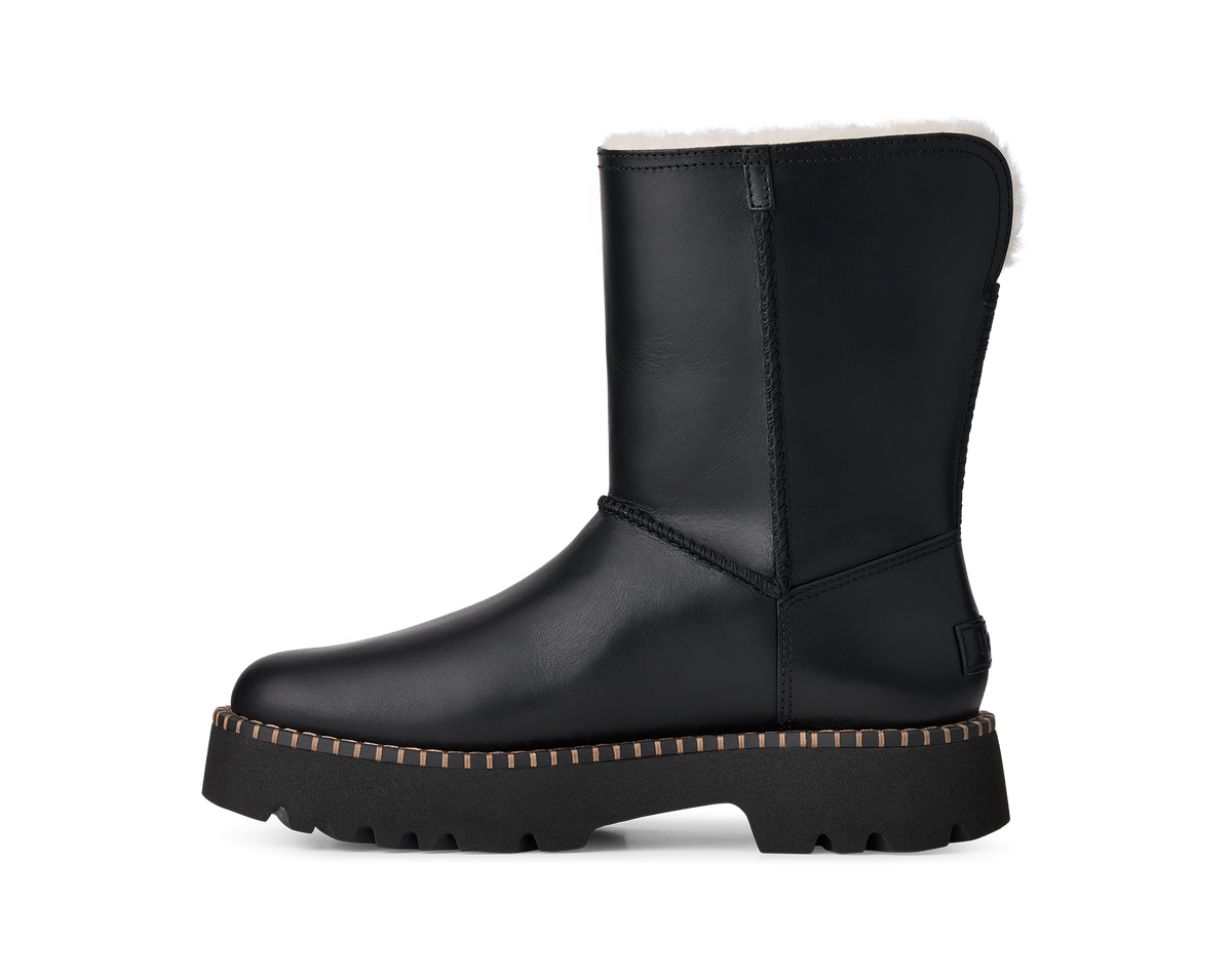 A single black mid-calf boot with a white shearling lining and a chunky lug sole, shown in a side profile on a white background.