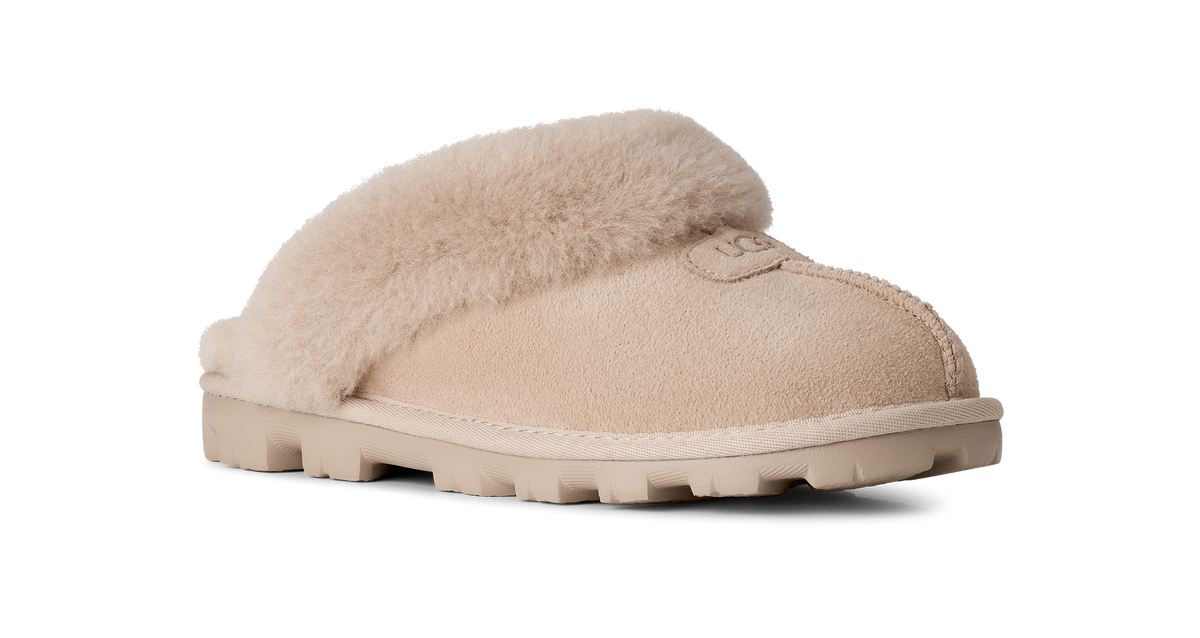 A single beige slip-on slipper with soft shearling-style fur trim and a chunky lug sole, shown on a clean white background.