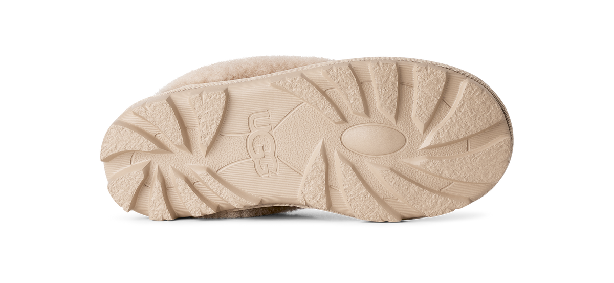 The beige sole of a UGG boot, showing the embossed UGG logo and textured tread pattern, photographed against a solid white background.