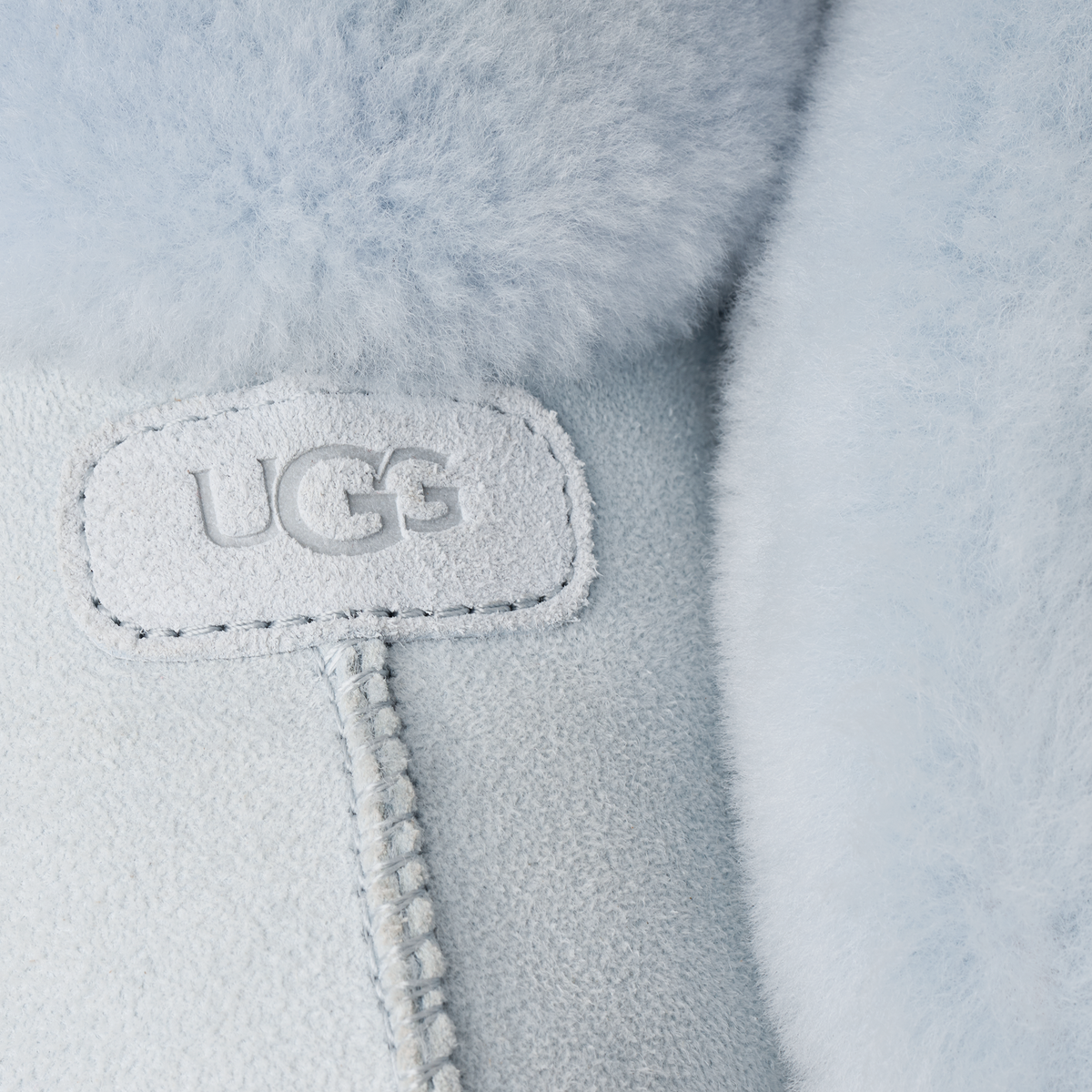 Close-up of a UGG logo on a light gray fleece fabric.