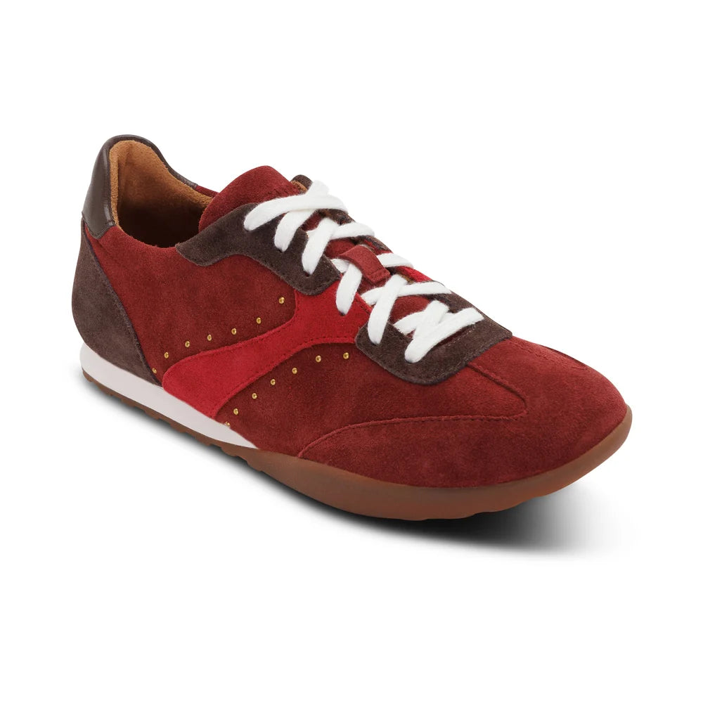 A low-top sneaker in red suede and dark brown leather, featuring white laces, a white midsole stripe, and a brown gum outsole, shown on a white background.