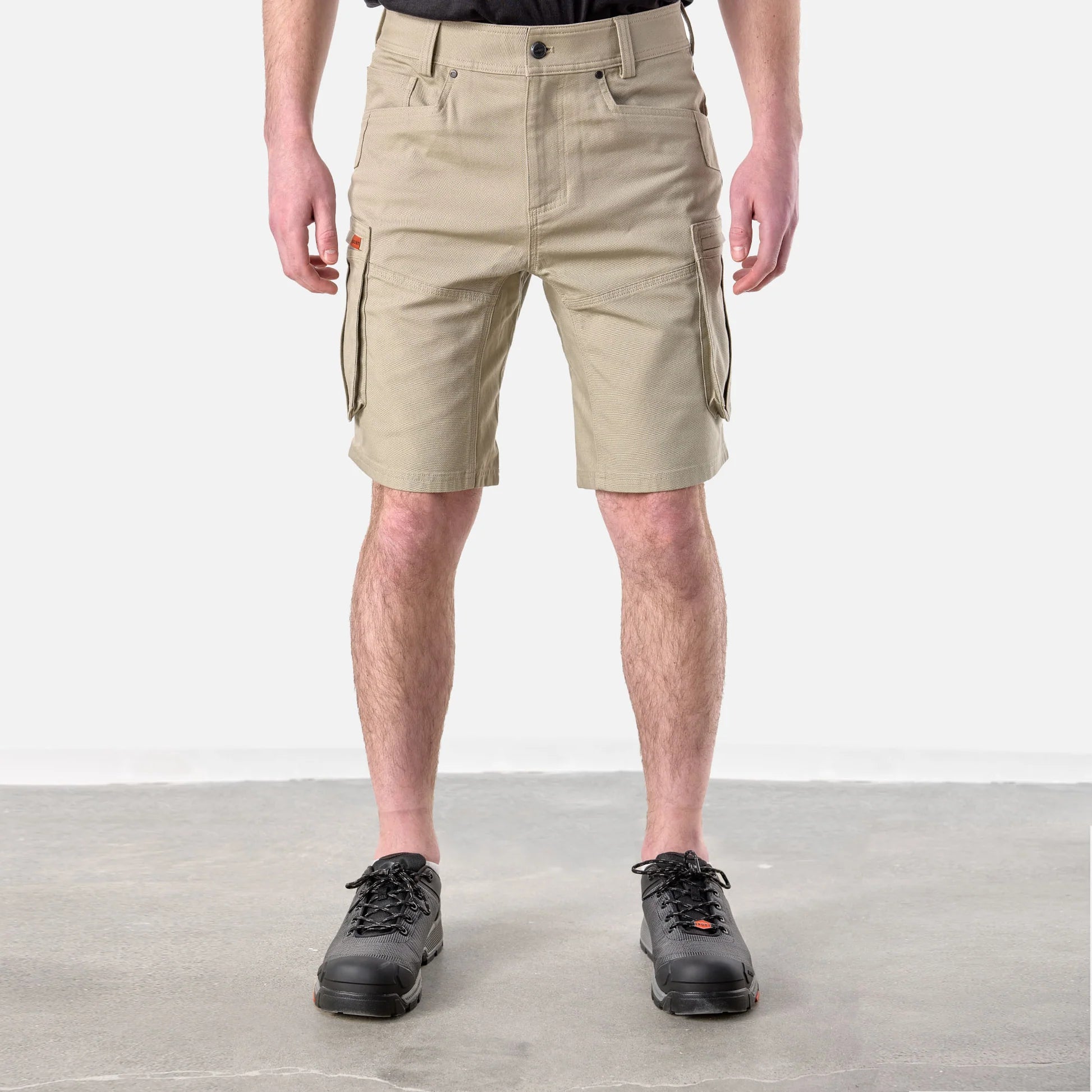 Person wearing beige cargo shorts on a plain background