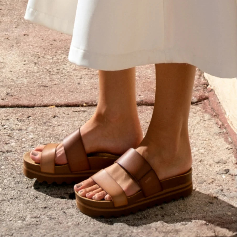 Brown sandals worn on a stone pavement