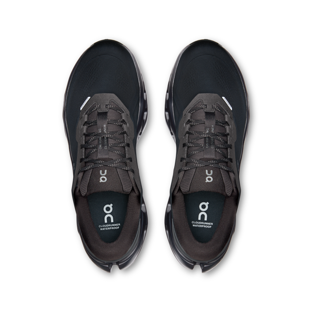 A pair of black and dark gray running shoes shown from a top-down view on a plain white background. The shoes feature the 'on' logo on the tongue and heel.