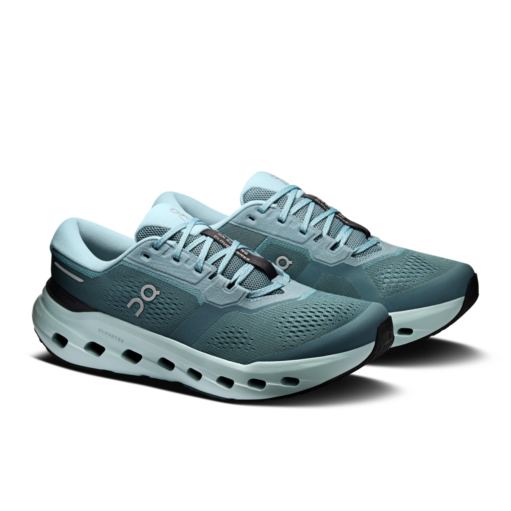 A pair of On running shoes in a muted teal-blue colorway, featuring a breathable mesh upper, a thick cushioned sole with visible air pockets, and the On logo on the side, set against a plain white background.