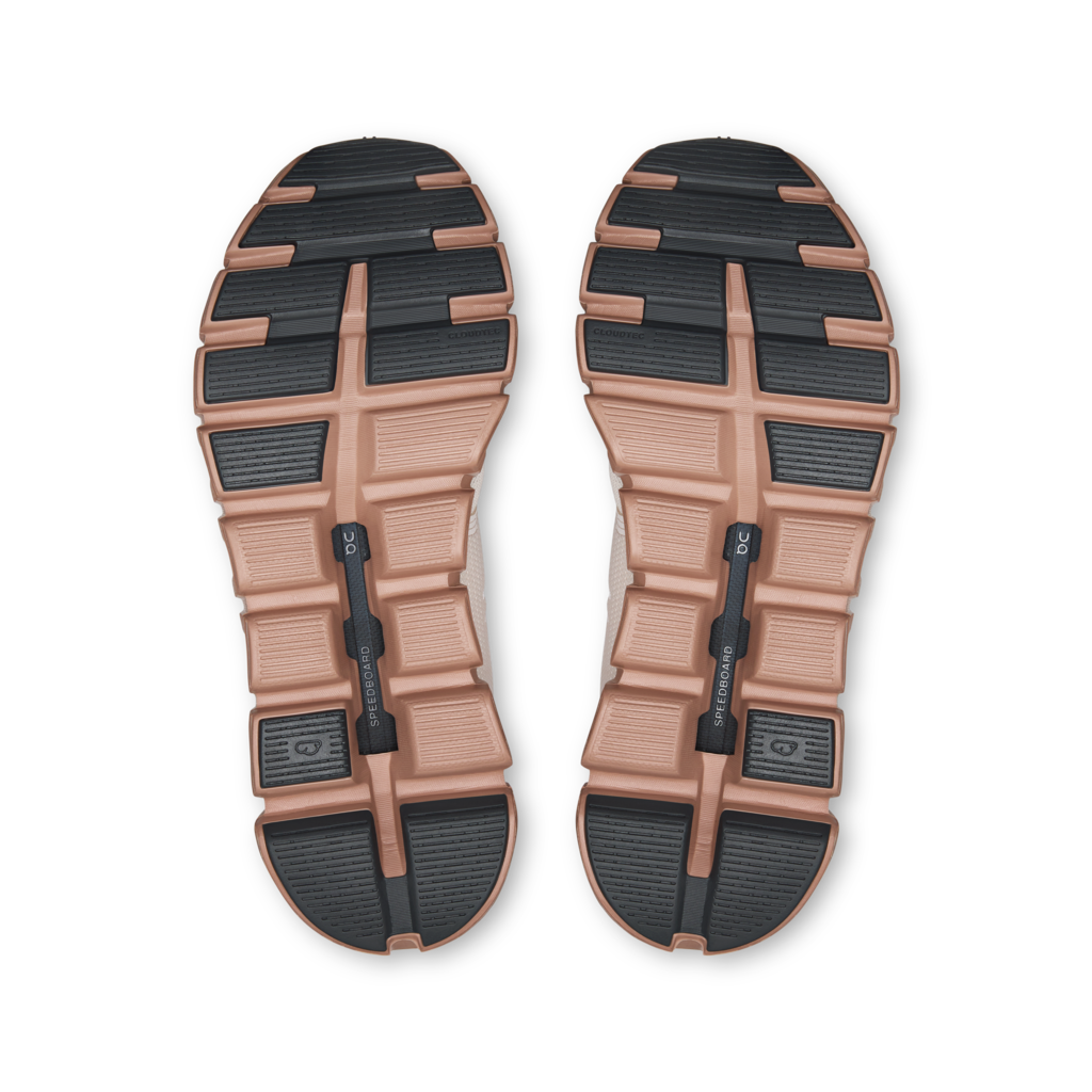 Top-down view of a pair of shoe soles, showing a tan and black treaded design with a central black heel strap and small printed branding.