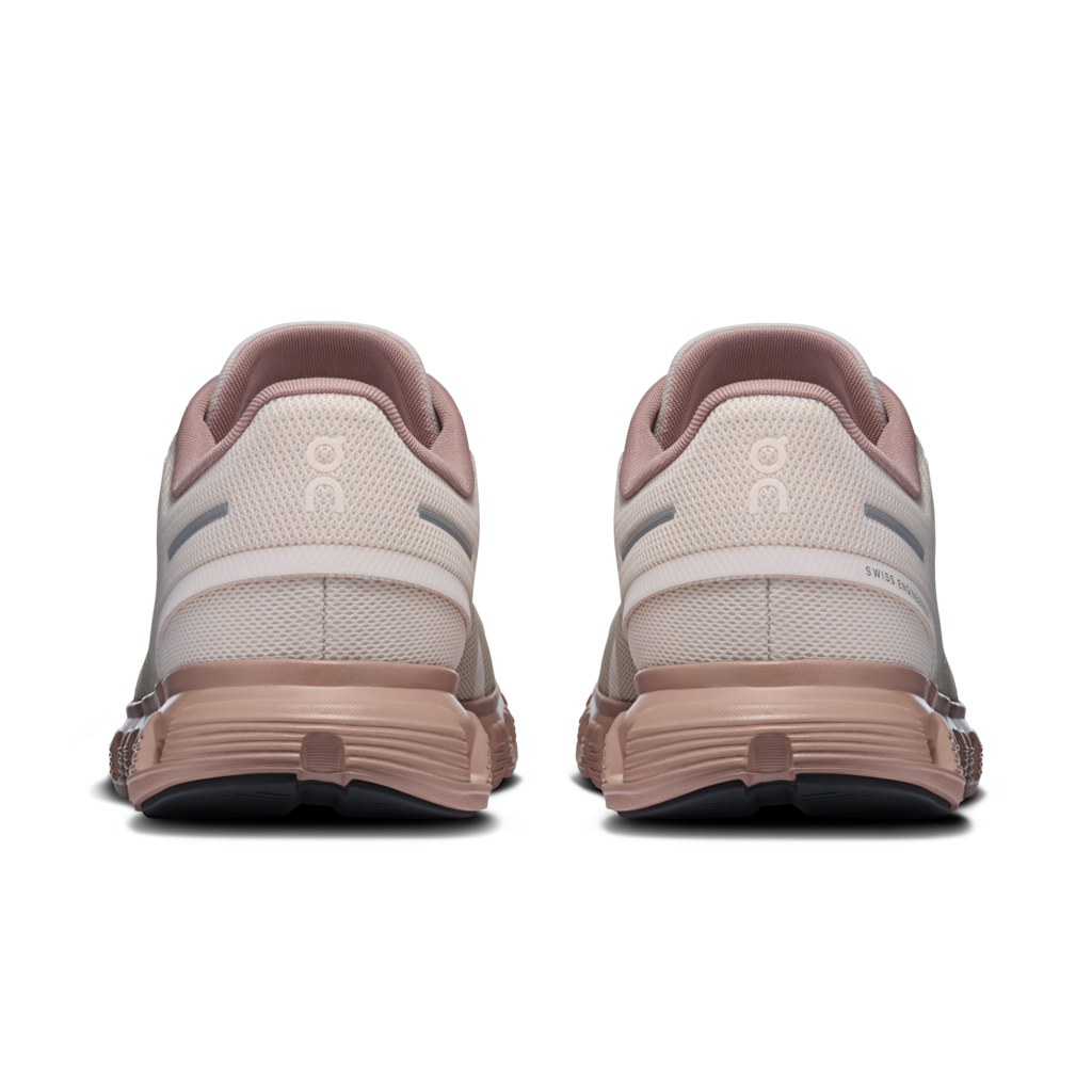 A pair of running shoes shown from the back, featuring a light beige mesh upper with dusty pink accents, a matching pink heel counter, and a chunky dusty pink midsole on a white background.