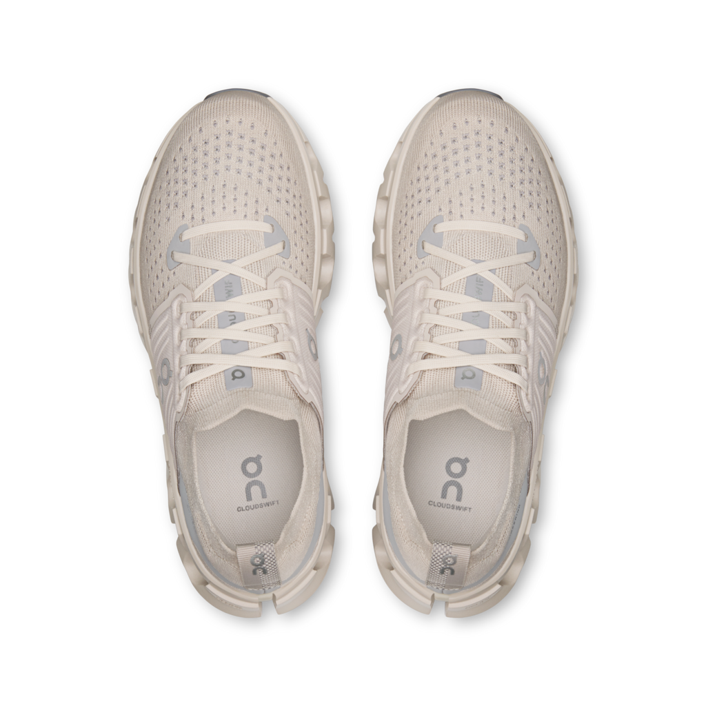 A pair of light beige running shoes shown from a top-down view on a clean white background. The shoes feature a breathable mesh upper, matching laces, and the 'on' logo printed on the insoles.