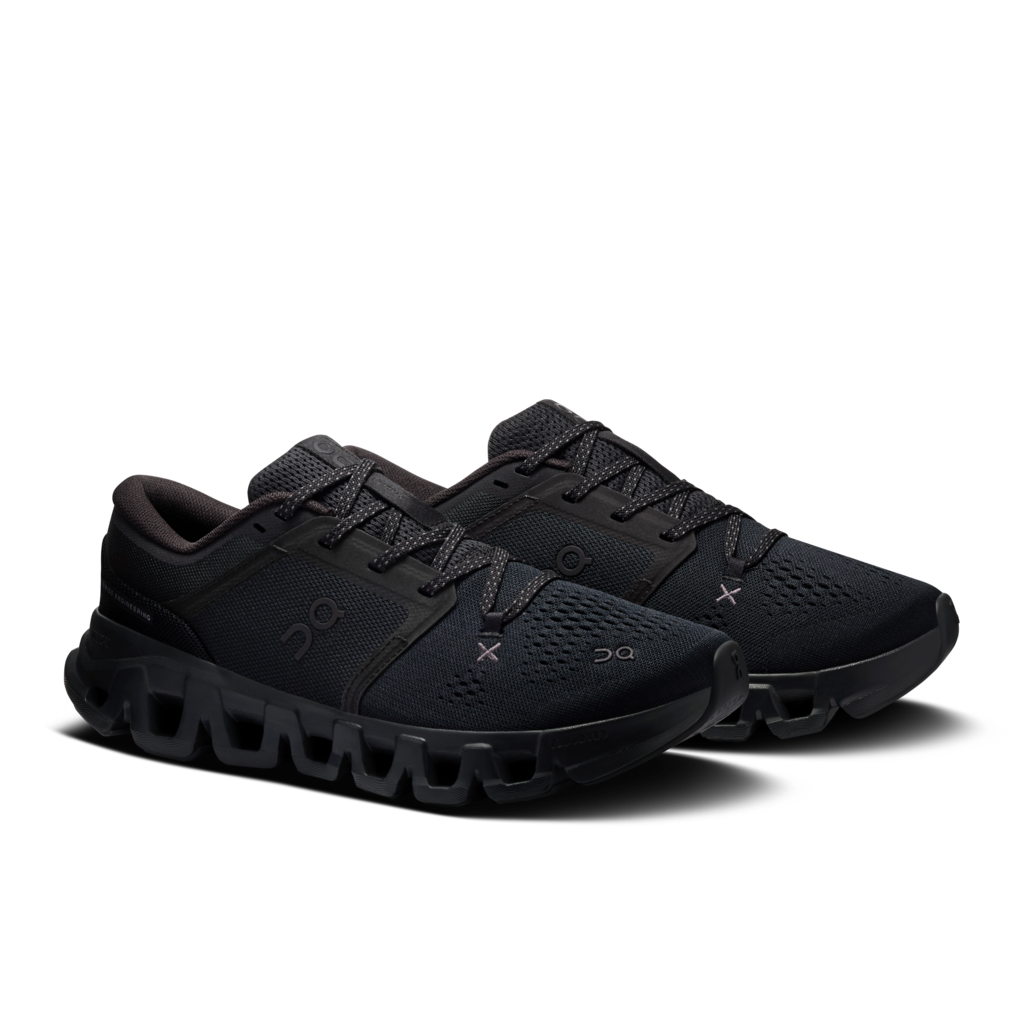 A pair of black On running shoes with textured mesh uppers, matching black laces, and a chunky black sole, displayed on a clean white background.