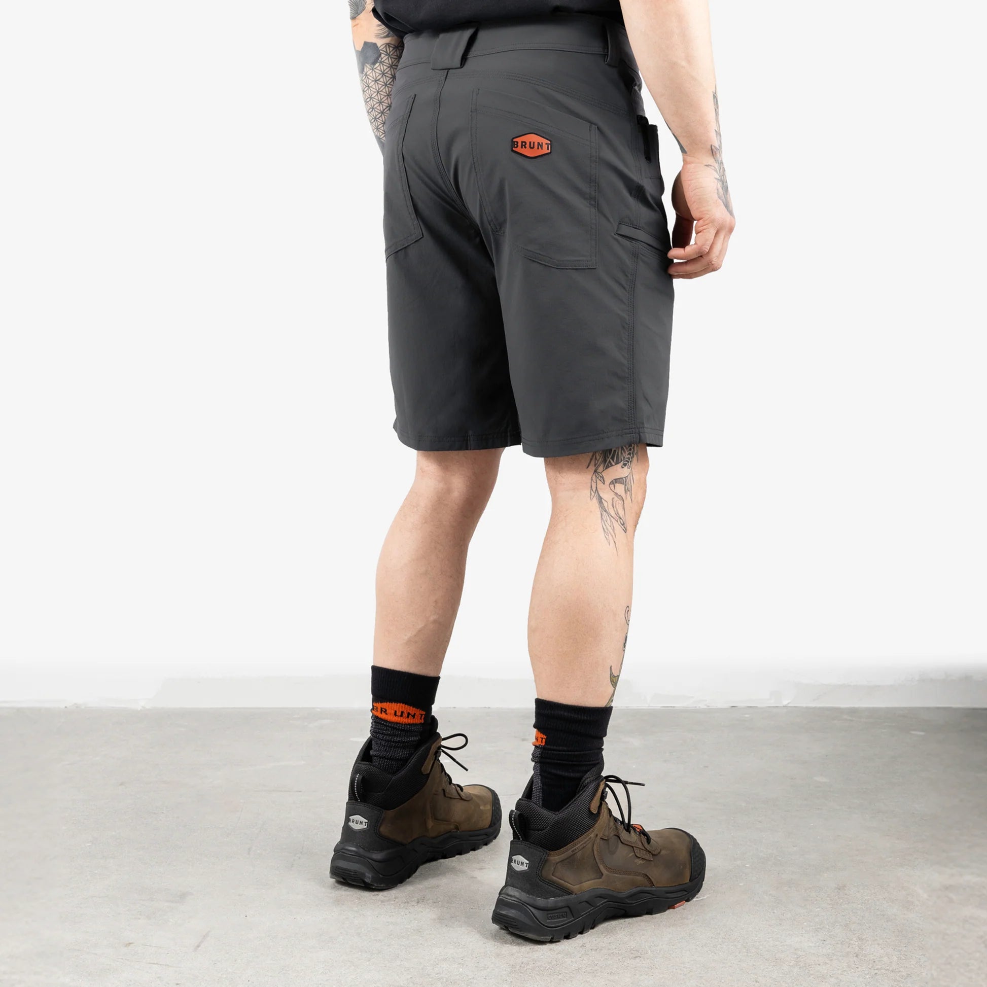 Person wearing gray shorts with a brand logo on a light background