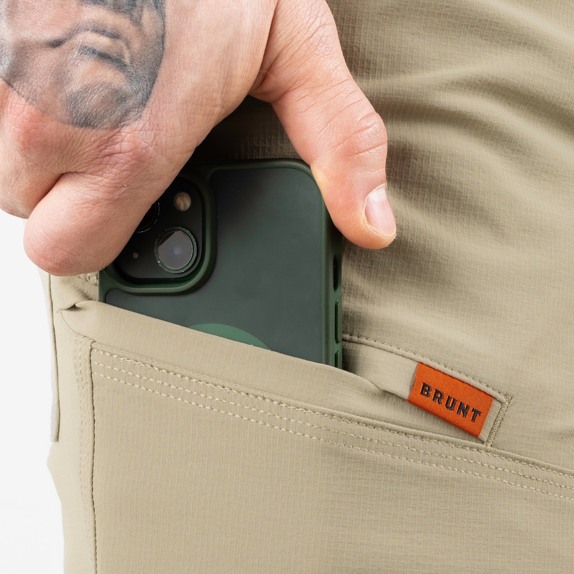 Person placing a phone into a pocket with a BRUNT label on the fabric.
