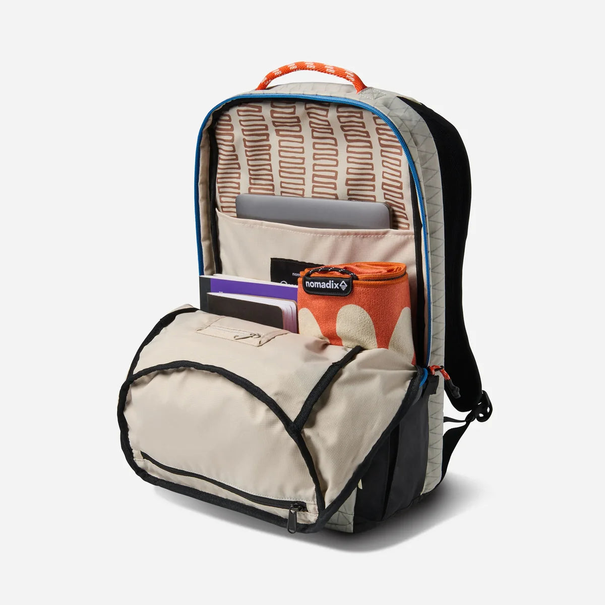 An open backpack shown on a white studio background, with its front zip pocket open and interior compartments visible. The bag is primarily beige and black with orange accents, including an orange top handle and an orange patterned item inside.