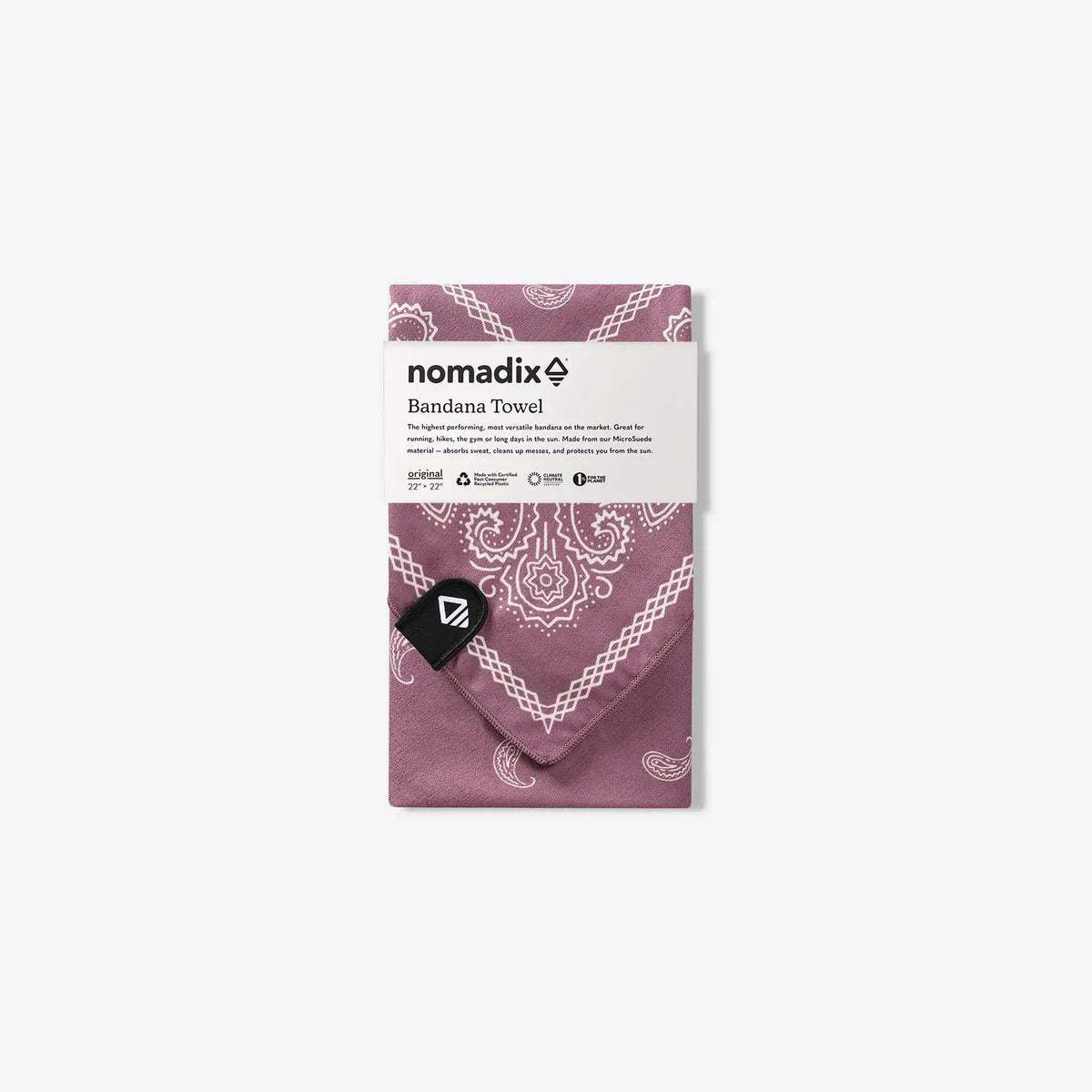 A folded Nomadix bandana towel in a dusty mauve-purple color with a white paisley pattern, wrapped in its white paper packaging with a black Nomadix logo tag.