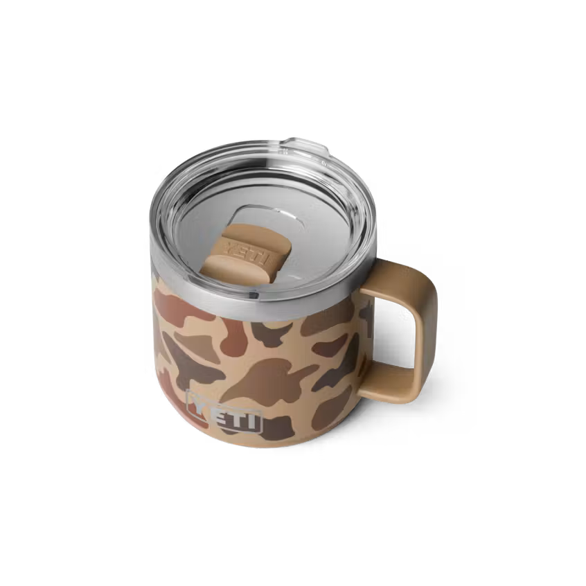 A YETI insulated mug with a brown and beige camouflage pattern, a stainless steel rim, and a tan handle, shown on a white background.