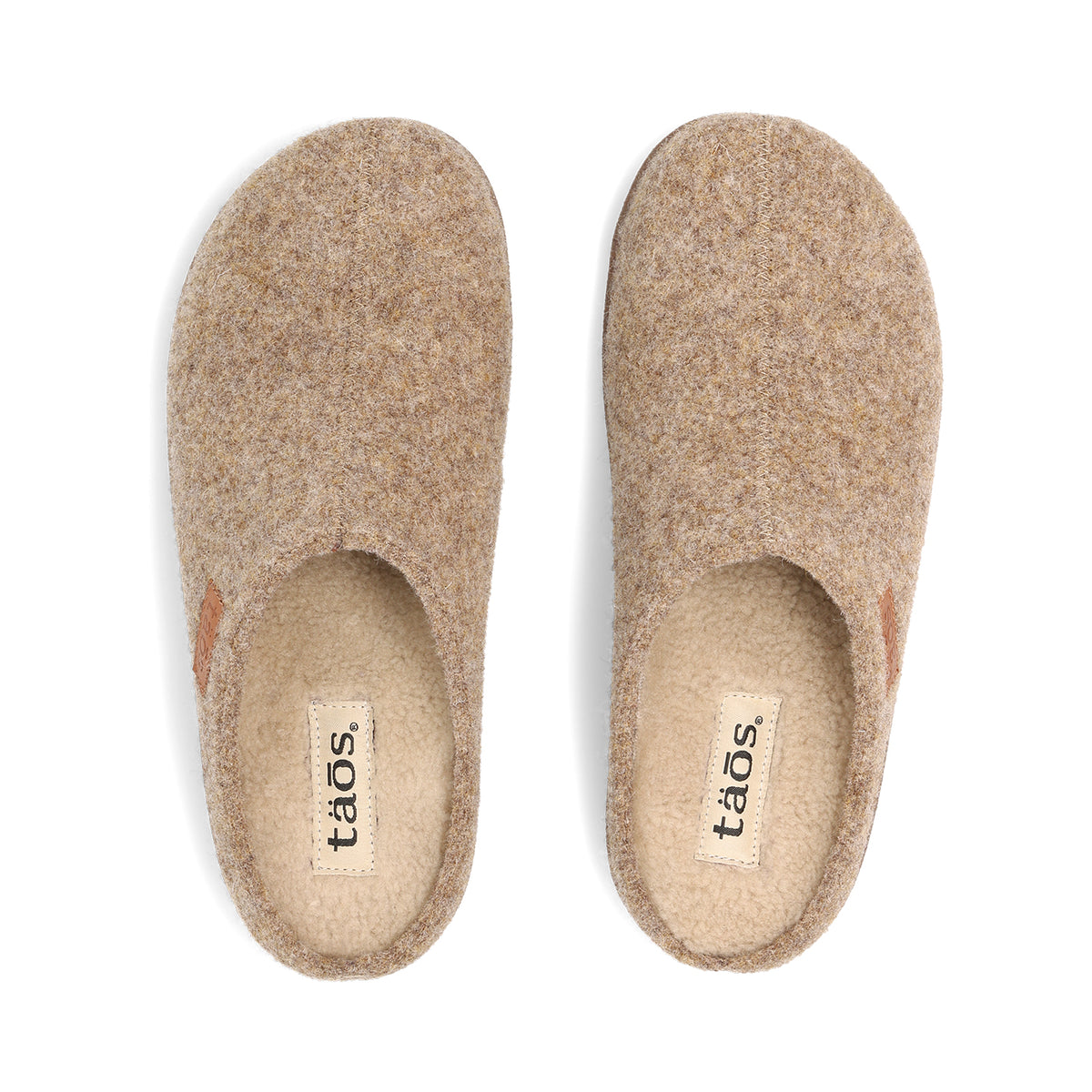 A pair of tan felt slip-on slippers shown from a top-down view on a white background. The brand name 'taos' is printed on a beige label inside the footbed.