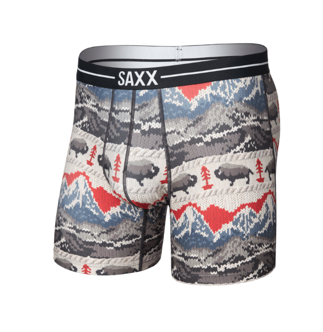 SAXX men's boxer briefs featuring a winter-themed print with bison, pine trees, and mountains in gray, blue, red, and beige, with a black and white elastic waistband.
