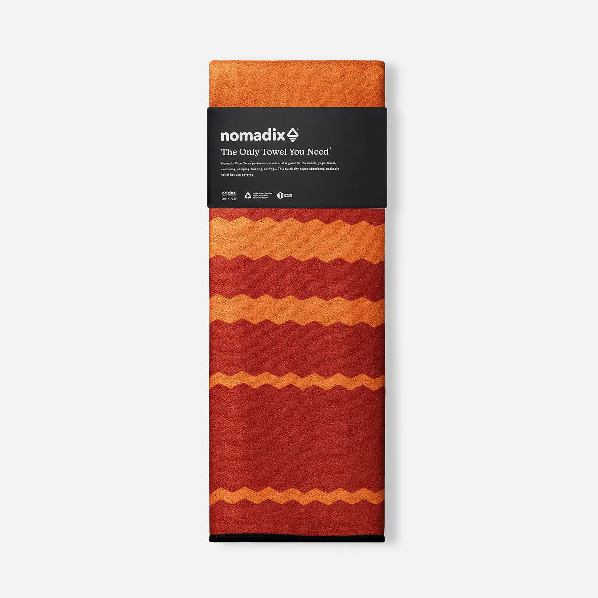 Folded towel with orange and red pattern and 'nomadix' branding on a white background