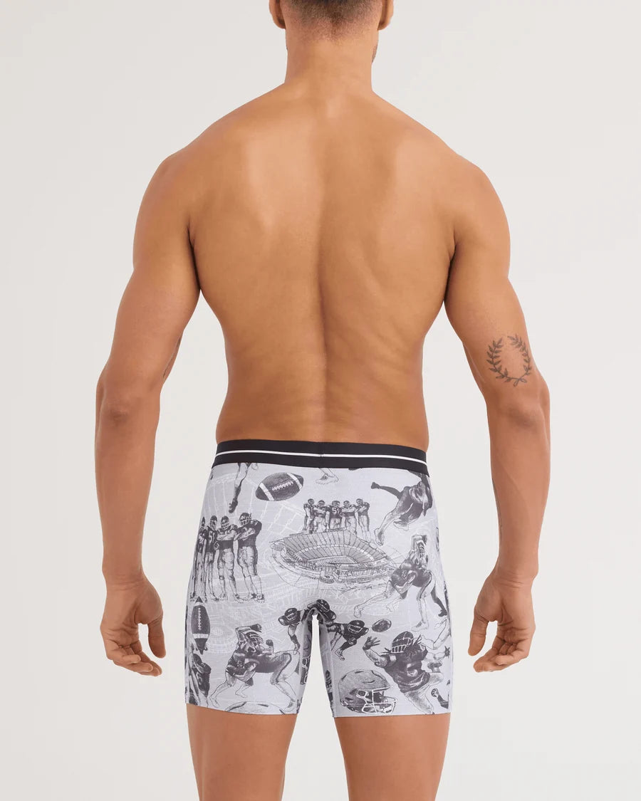 Rear view of a shirtless male model wearing boxer briefs with a black and white football stadium graphic print on a light gray background.