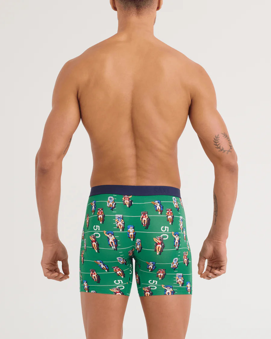 Man wearing green boxer briefs with a pattern on a white background