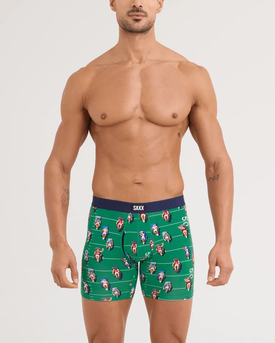 Man wearing green boxer briefs with a pattern, standing against a plain background
