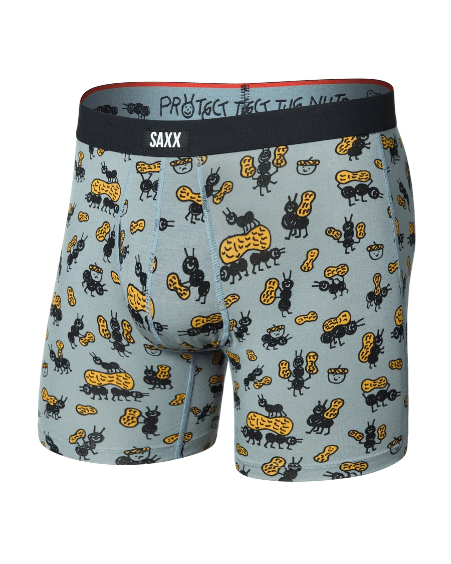 A pair of SAXX men's boxer briefs featuring a light blue-gray background with a cartoon pattern of black ants and yellow peanuts, finished with a black waistband.