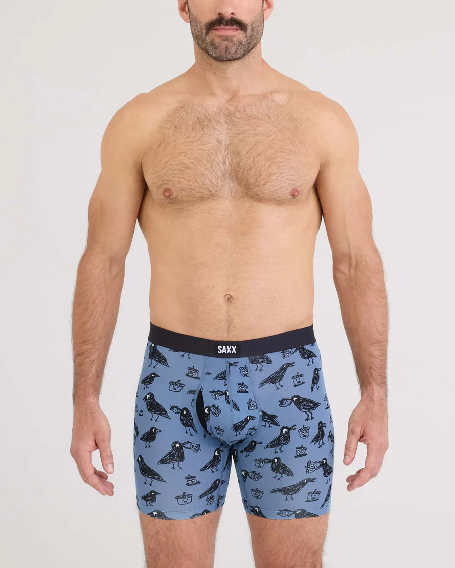 Man wearing blue boxer briefs with bird pattern and Saxx branding.