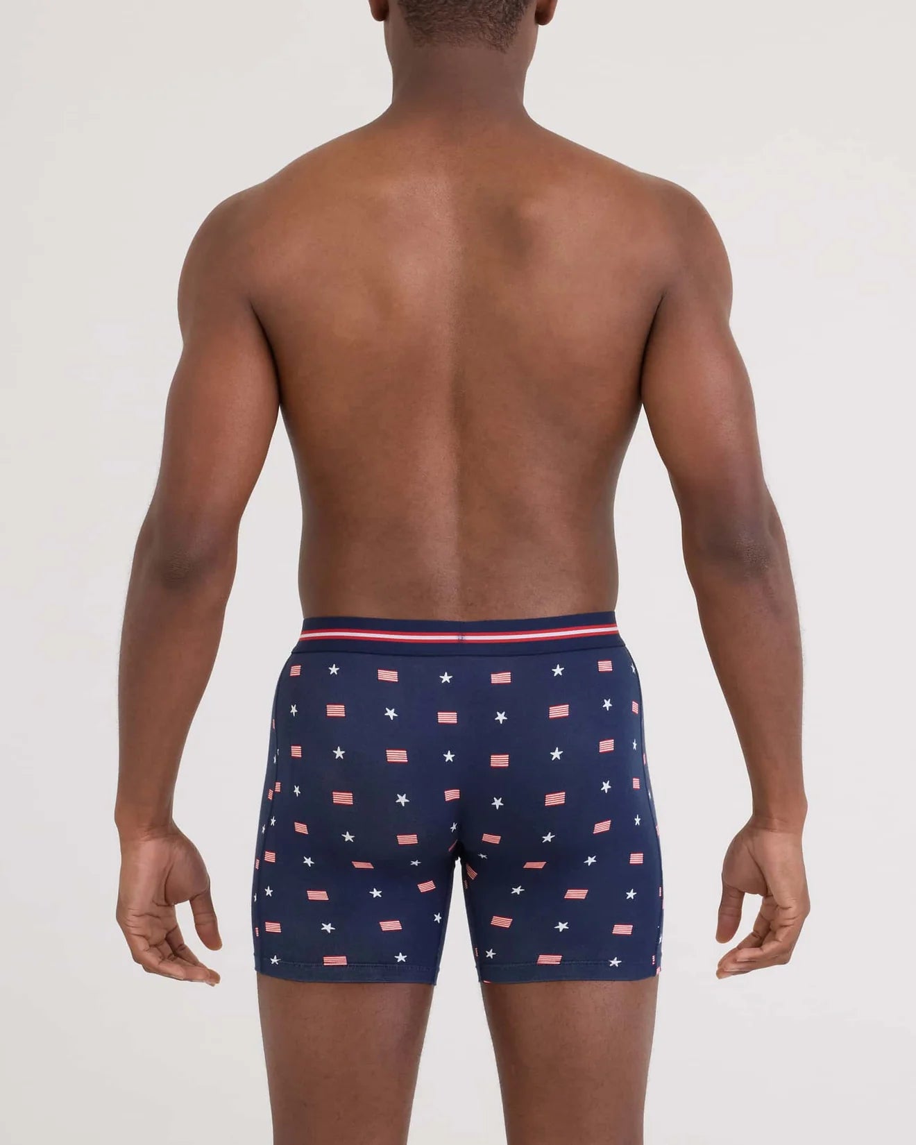 Man wearing navy blue boxer briefs with a pattern of stars and stripes on a plain background