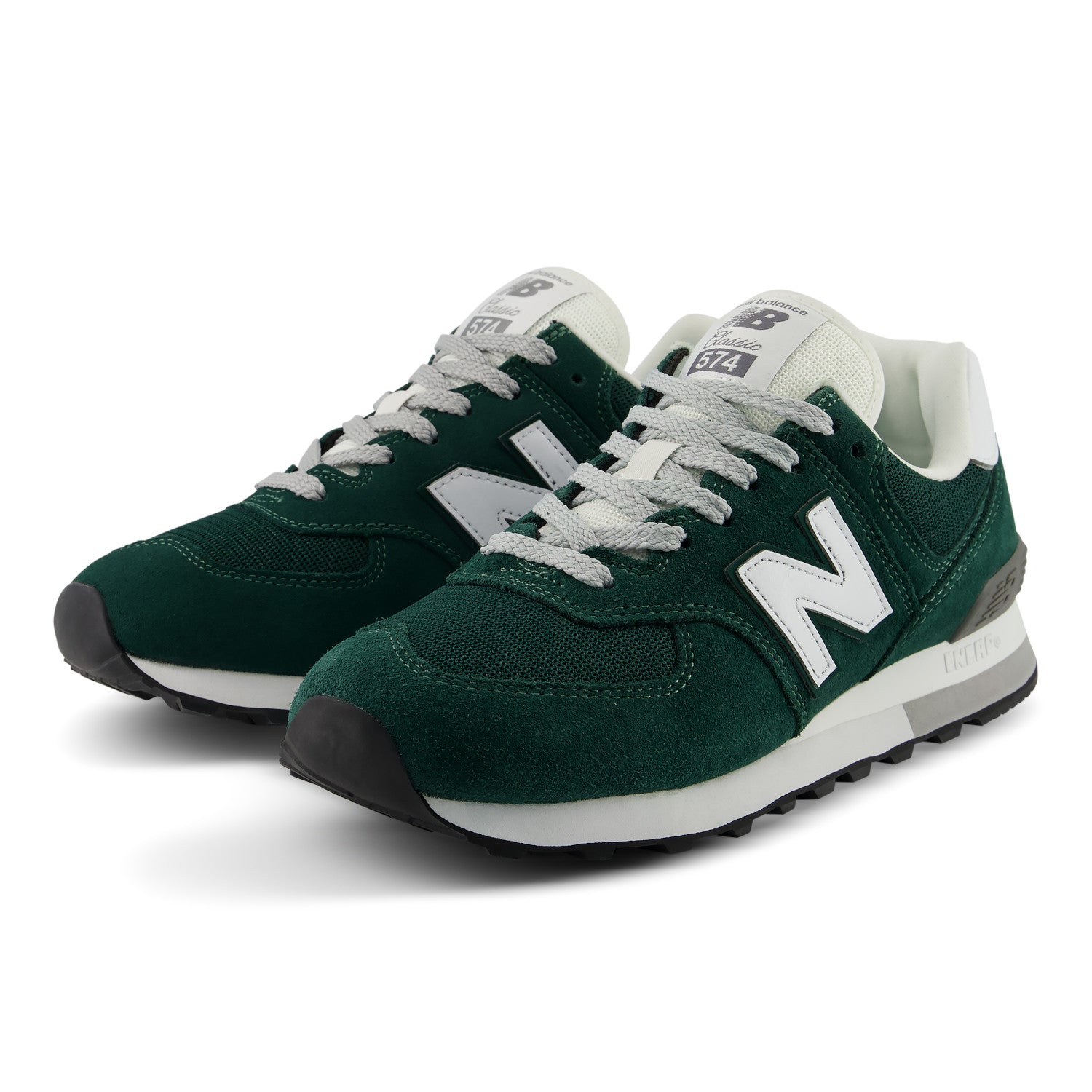 A pair of New Balance 574 sneakers in dark forest green suede and mesh, featuring white 'N' logos, white laces, and white midsoles with black outsoles.