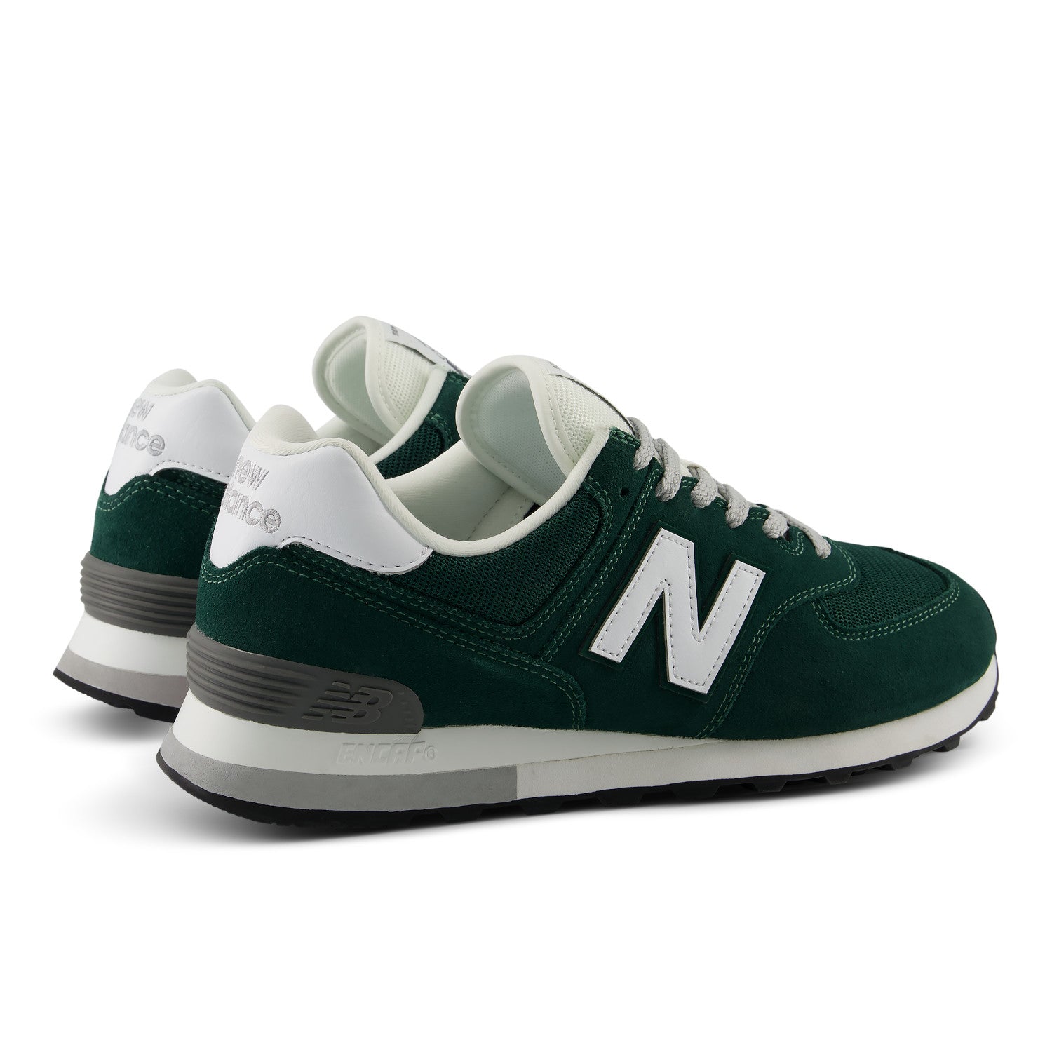 A pair of New Balance 574 sneakers in forest green suede and mesh, featuring white laces, a white 'N' logo, and a white and gray midsole, set against a plain white background.