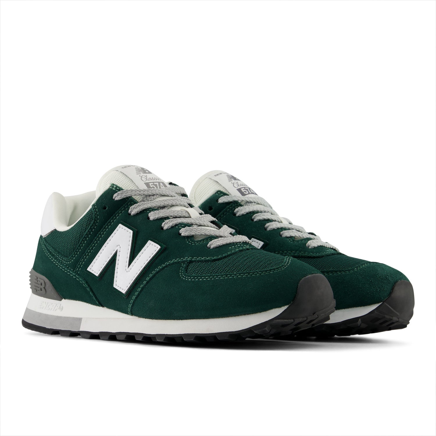 A pair of New Balance 574 sneakers in forest green suede and mesh, featuring a prominent white 'N' logo, white laces, and a white midsole with dark gray accents.