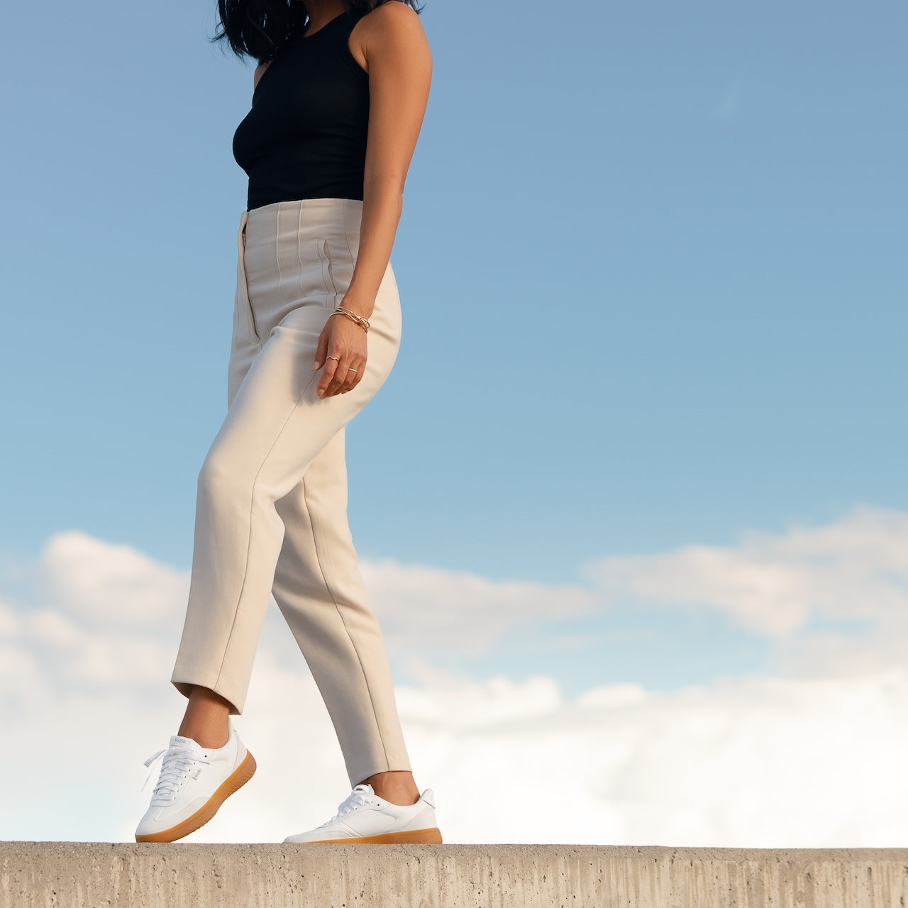 Person wearing beige pants and white sneakers against a blue sky.